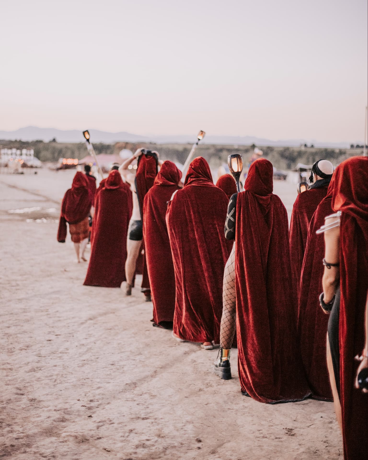 A procession of camp members in red cloaks crossing the playa